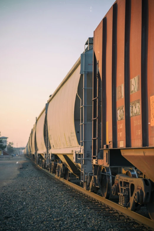 a large long train on a steel track, by Jason Felix, unsplash, taken at golden hour, trading depots, vsco film grain, vehicles