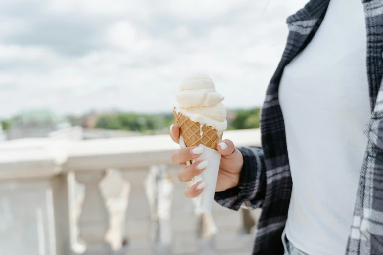 a woman holding an ice cream cone in her hand, by Emma Andijewska, trending on pexels, white, seasonal, 15081959 21121991 01012000 4k