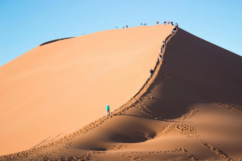 a group of people standing on top of a sand dune, by Peter Churcher, pexels contest winner, hurufiyya, tiny person watching, curved, 3 5 mm slide, 5 0 0 px