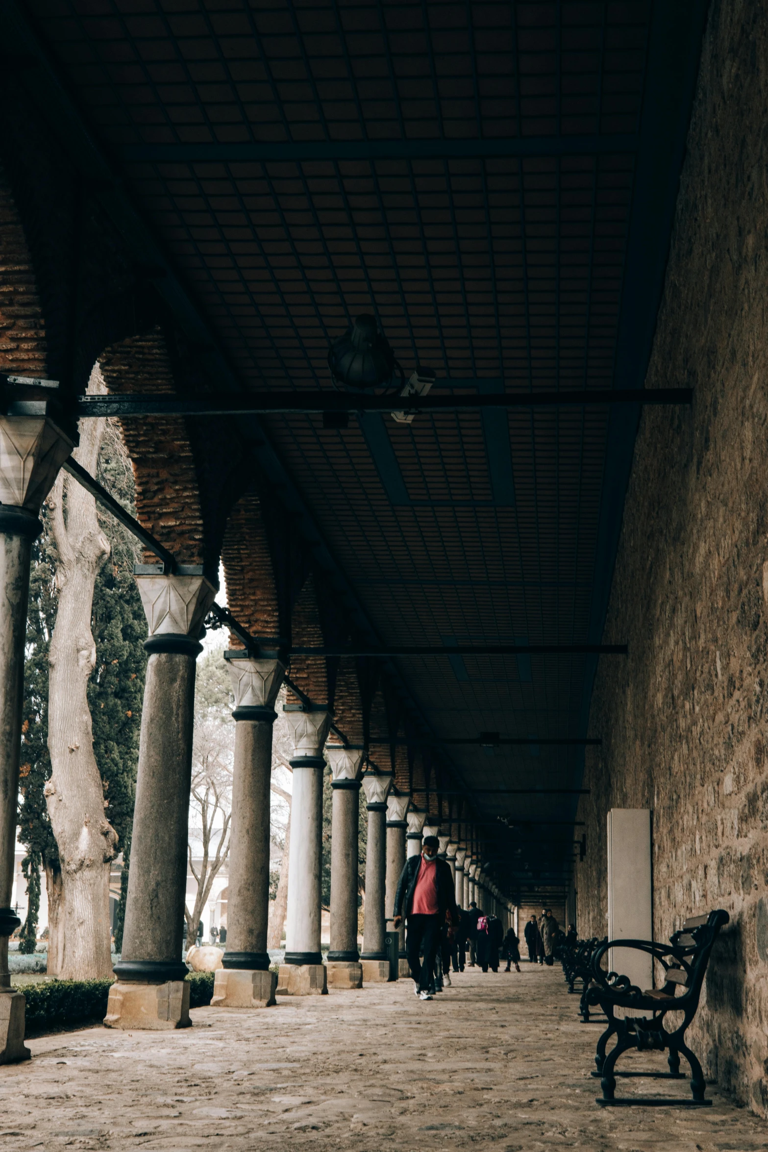 a row of benches sitting under a covered walkway, a picture, pexels contest winner, renaissance, the fall of constantinople, low quality photo, colonnade, cypresses