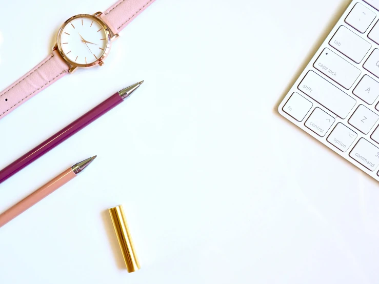 a pink watch sitting on top of a desk next to a keyboard, trending on pexels, minimalism, pencils, white background : 3, gold, background image