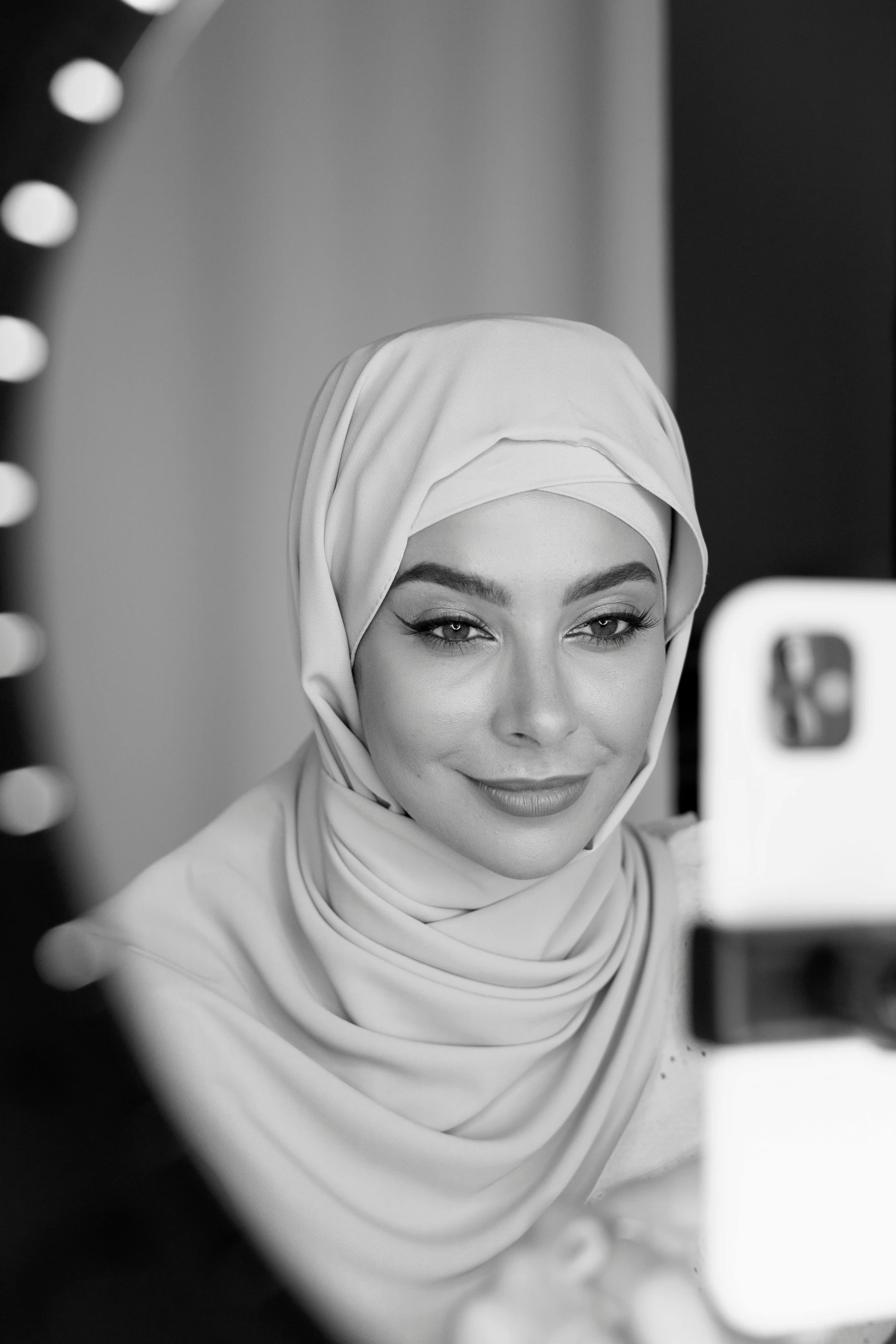 a woman taking a picture of herself in a mirror, a black and white photo, inspired by Maryam Hashemi, shutterstock, hurufiyya, white hijab, professional headshot, portait of haifa wehbe, youtuber