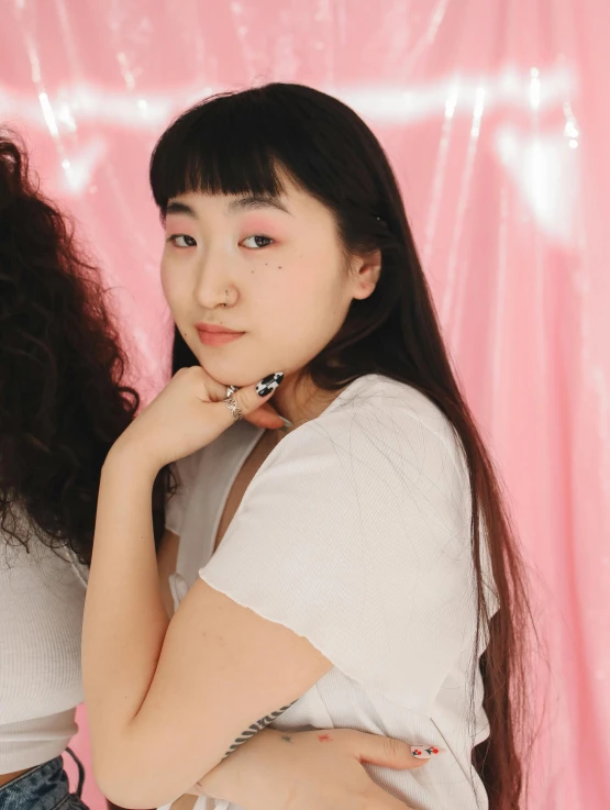 a couple of women standing next to each other, an album cover, inspired by Kim Jeong-hui, trending on pexels, realism, fluffy bangs, pink volumetric studio lighting, ethnicity : japanese, lily frank