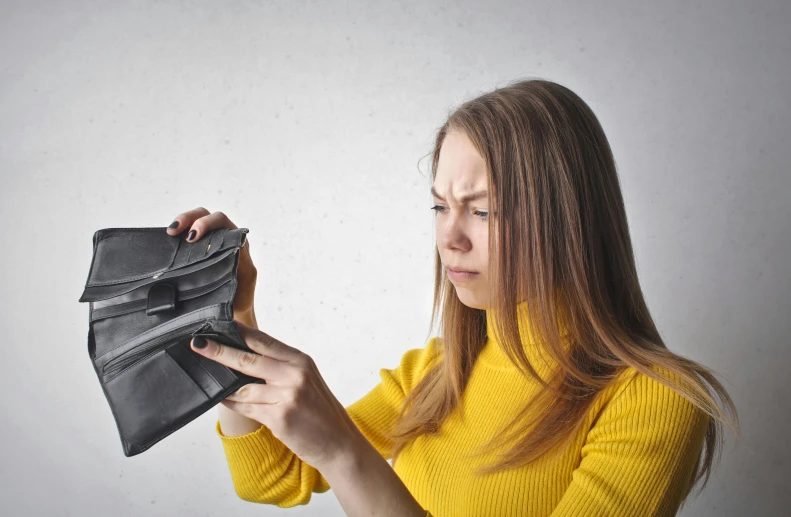 a woman holding an empty wallet in front of her face, pexels, frustrated expression, carrying a saddle bag, avatar image