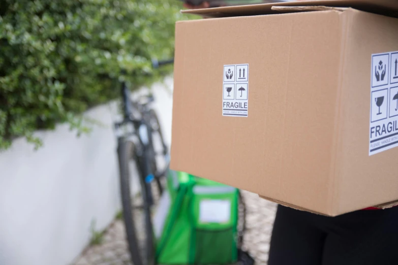 a person carrying a box with stickers on it, exterior shot, angled shot, digital image