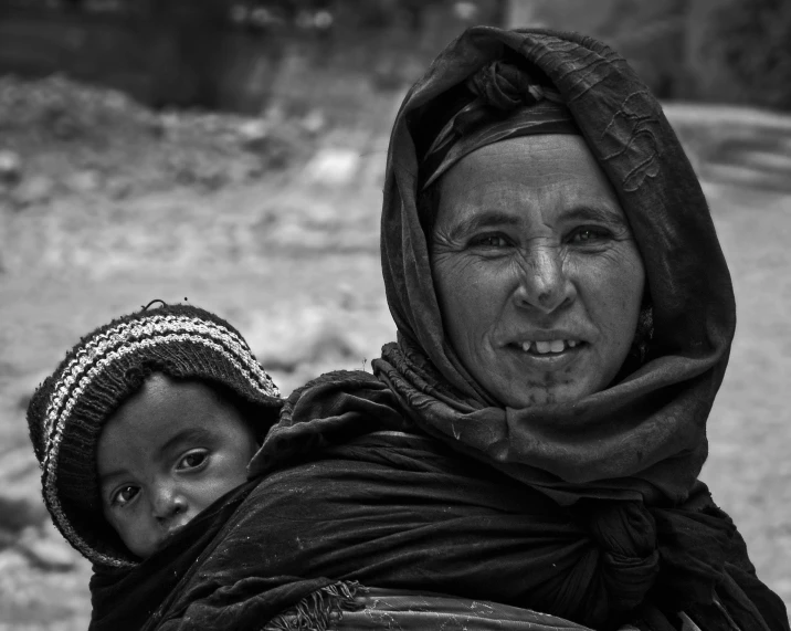 a black and white photo of a woman carrying a child, by Ibrahim Kodra, pexels contest winner, hurufiyya, moroccan, beautiful himalayan woman, indigenous, resting