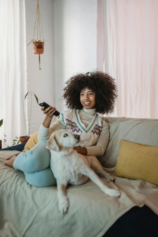 a woman sitting on a couch holding a remote control, a cartoon, trending on pexels, subject: dog, with afro, romantic lead, spring season