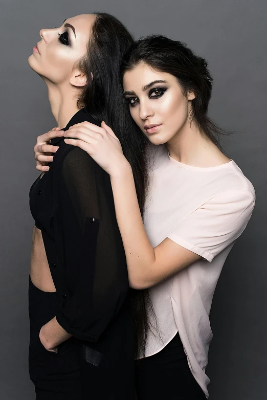a couple of women standing next to each other, an album cover, by Lucia Peka, shutterstock, gorgeous young model, hugging each other, whitebangsblackhair, fashion studio lighting