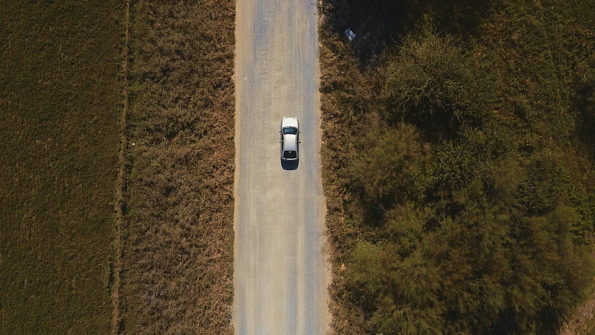 an aerial view of a car driving down a country road, alana fletcher, andrew tate, **cinematic, rectangle