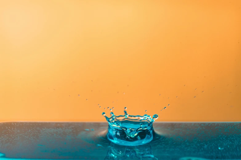 a splash of water on top of a sink, trending on unsplash, visual art, in front of an orange background, floating crown, blue background colour, water feature