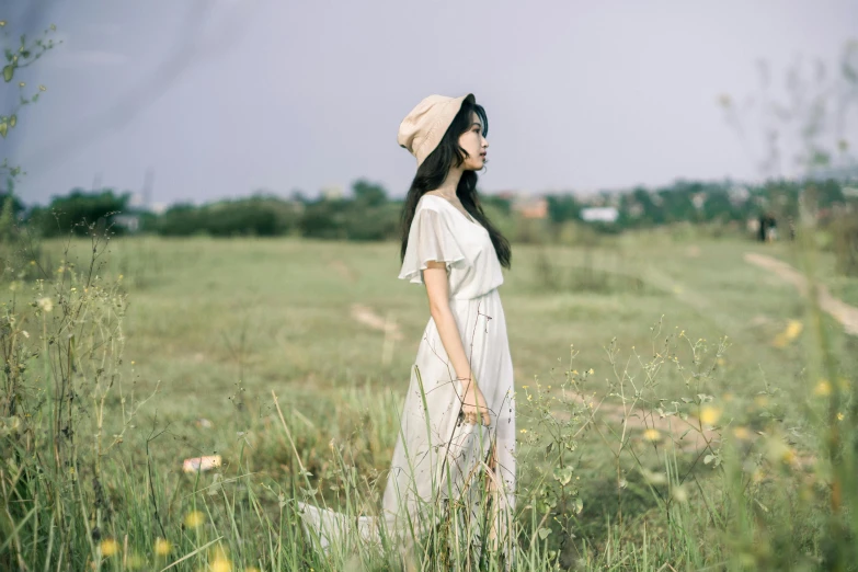 a woman standing in a field of tall grass, by Tan Ting-pho, unsplash, minimalism, simple cream dress, with hat, bae suzy, anime thai girl