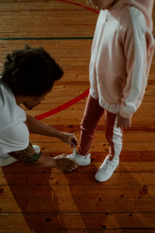 a couple of kids standing on top of a wooden floor, laces and ribbons, 2 1 savage, yzy gap, reaching out to each other