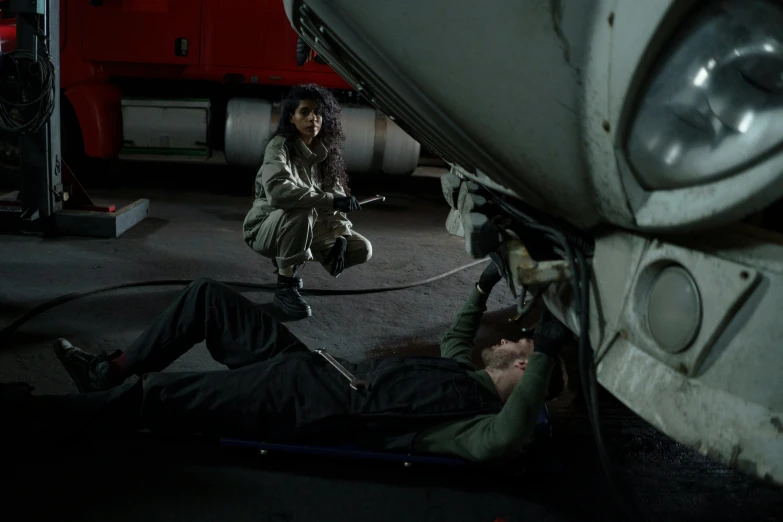 two people working on a vehicle in a garage, a portrait, by Jeffrey Smith, z nation, air force jumpsuit, romantic lead, sza