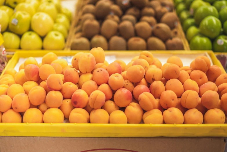 a box filled with lots of different types of fruit, by Nicolette Macnamara, pexels, bauhaus, in shades of peach, inside a supermarket, yellow, manuka