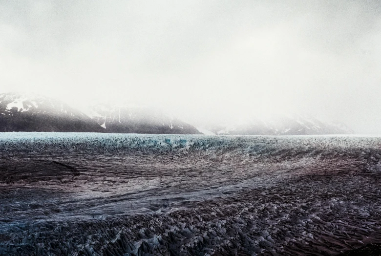 a large body of water with mountains in the background, inspired by Elsa Bleda, pexels contest winner, hyperrealism, icy glaciers, fog on ground, apocalyptic tumultuous sea, abstract landscape