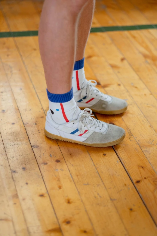 a person standing on top of a wooden floor, inspired by Graham Forsythe, dribble, wearing kneesocks, 1 red shoe 1 blue shoe, cream, 8 0 s sport clothing