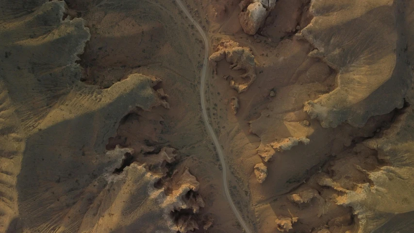 an aerial view of a dirt road in the desert, inspired by Filip Hodas, photorealism, looking down a cliff, chiseled features, satellite imagery, detailed scenery —width 672