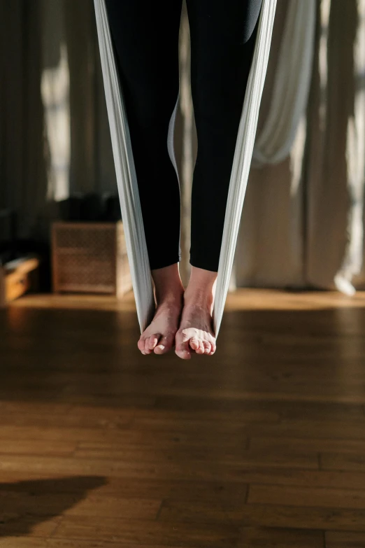 a woman standing on a hammock in a room, by Jessie Algie, trending on pexels, arabesque, in a jumping float pose, foot wraps, top down photo, medium close up shot