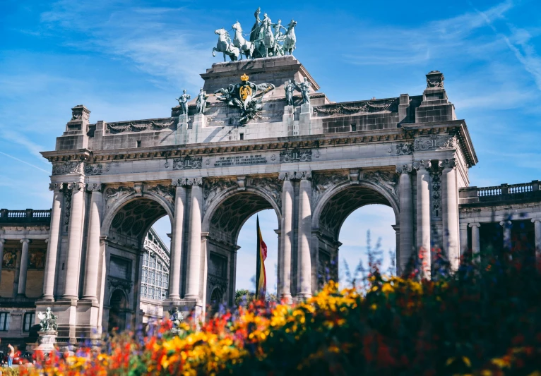 a large building with a statue on top of it, a marble sculpture, by Julia Pishtar, pexels contest winner, art nouveau, massive arch, city park with flowers, belgium, military