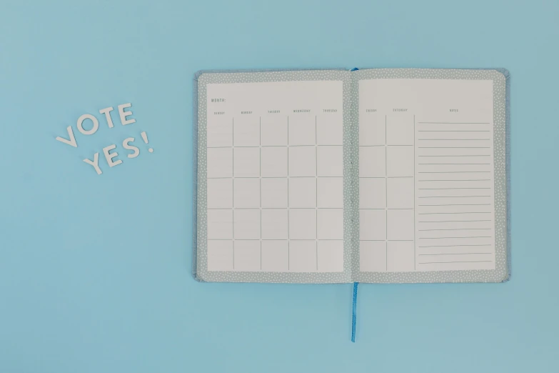 an open notebook sitting on top of a blue surface, by Rachel Reckitt, happening, female calendar, grey and blue theme, lined in cotton, polka dot