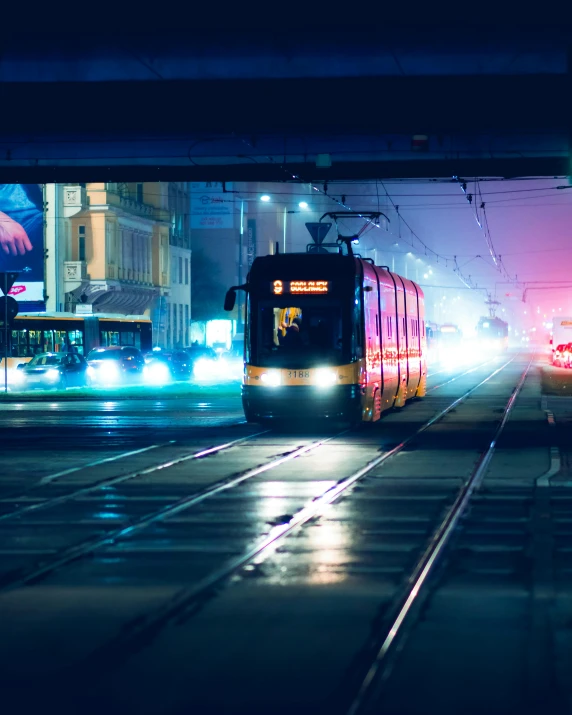 a train traveling down a city street at night, by Adam Marczyński, pexels contest winner, lgbtq, trams ) ) ), square, high quality photo