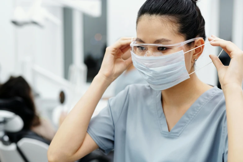 a woman wearing a face mask in a dentist's office, trending on pexels, hurufiyya, nurse costume, darren quach, wearing round glasses, profile image