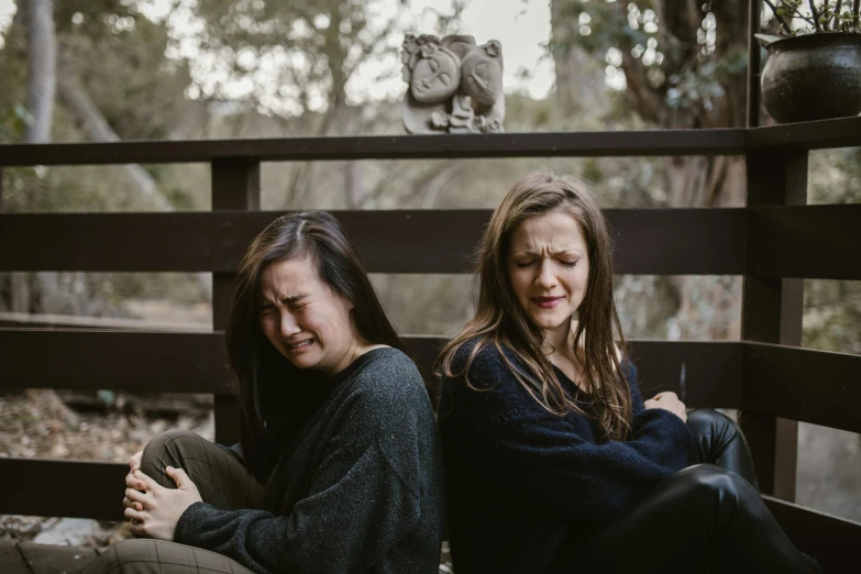 a couple of women sitting on top of a wooden bench, unsplash, realism, grimacing, “ iron bark, crying and puking, ruan jia and mandy jurgens