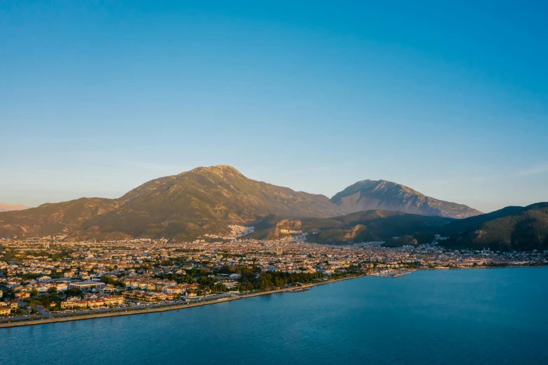 a large body of water with a mountain in the background, pexels contest winner, hurufiyya, port city, marbella landscape, birdseye view, golden dawn