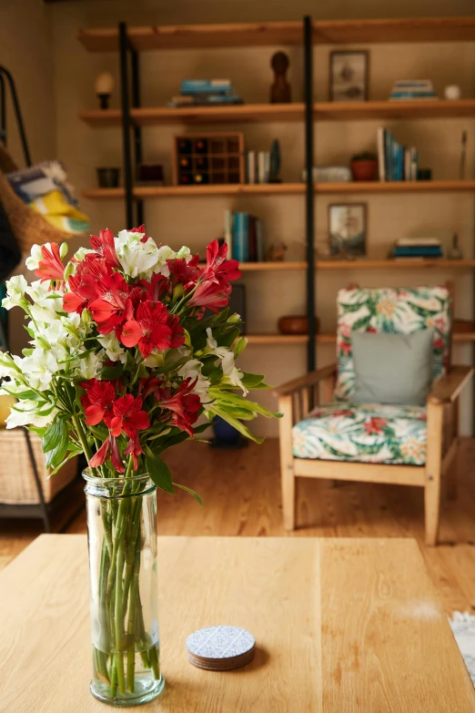 a vase of flowers sitting on top of a wooden table, by Gawen Hamilton, crimson and white color scheme, living room, tropical flowers, close together