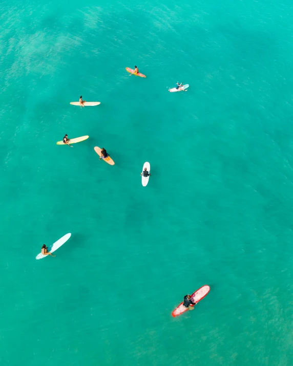 a group of people riding surfboards on top of a body of water, from above