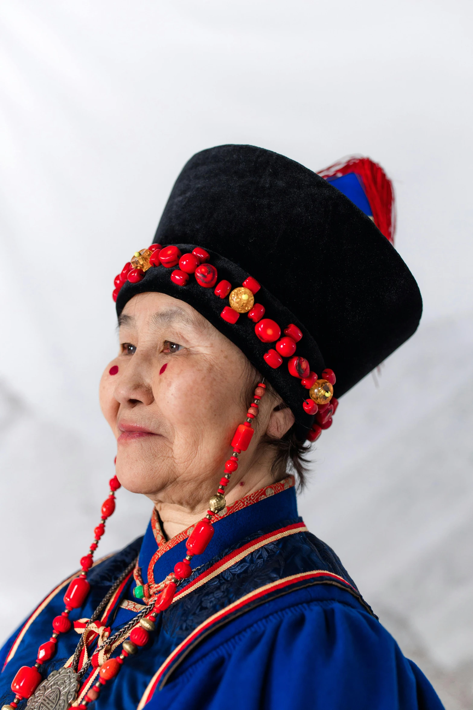 a woman wearing a black hat and red beads, an album cover, inspired by Hu Zao, pexels contest winner, cloisonnism, inuk, red and blue garments, traditional russia, high resolution image