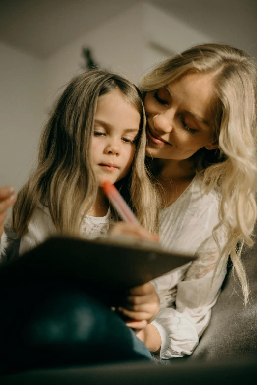 a woman and a little girl sitting on a couch, a child's drawing, pexels contest winner, blond, holding notebook, gif, teacher