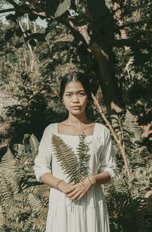 a woman in a white dress standing in front of a tree, inspired by Ruth Jên, pexels contest winner, sumatraism, ((portrait)), foliage clothing, lofi, south east asian with long