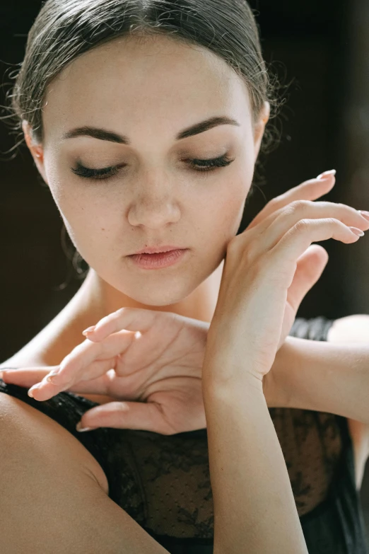 a woman in a black dress holding her hands to her chest, trending on pexels, arabesque, portrait of a ballerina, closes her eye, synthetic bio skin, prima ballerina