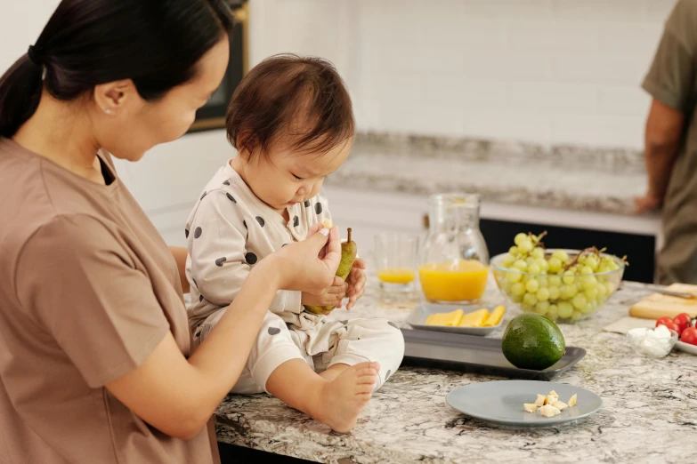 a woman holding a baby in a kitchen, pexels contest winner, plates of fruit, manuka, plating, profile image