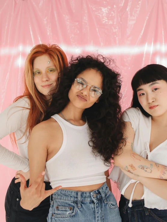 a group of three women standing next to each other, inspired by Ren Hang, trending on pexels, feminist art, transparent glasses, mixed race, soft aesthetic, pink studio lighting