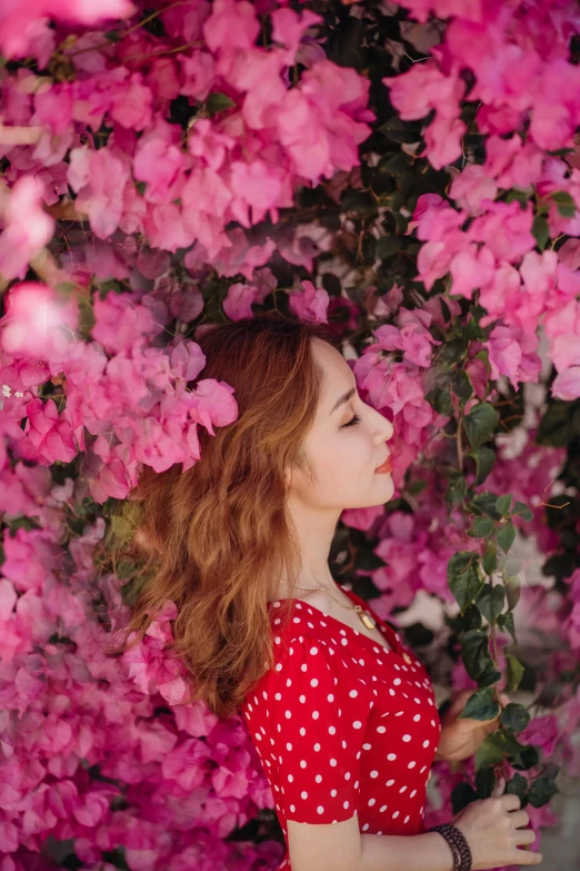 a woman standing in front of a bush of pink flowers, inspired by Oleg Oprisco, pexels contest winner, profile image, ( redhead, bougainvillea, high-quality 4k portrait