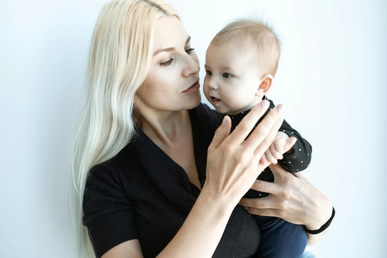 a woman holding a baby in her arms, pexels contest winner, antipodeans, blonde and attractive features, white haired, black, anastasia ovchinnikova