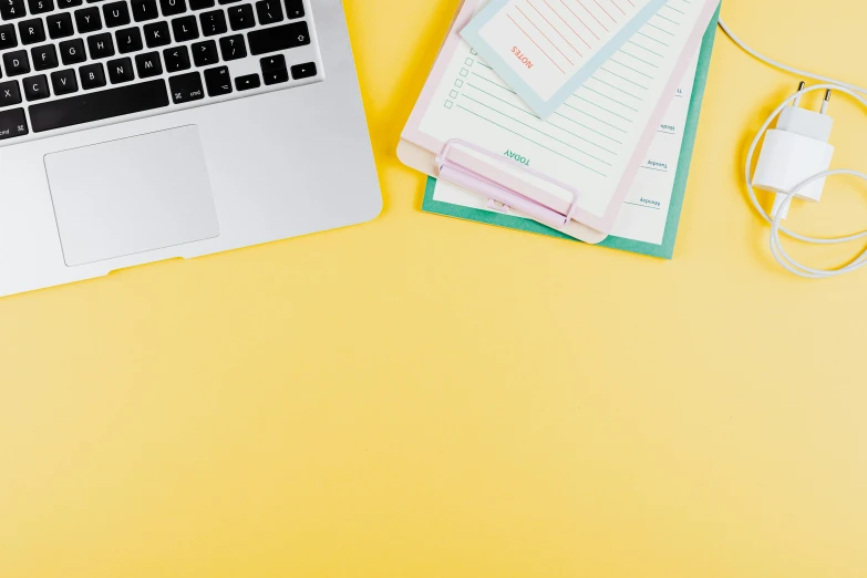 a laptop computer sitting on top of a yellow desk, by Carey Morris, trending on pexels, papers, background image, pastel', various items