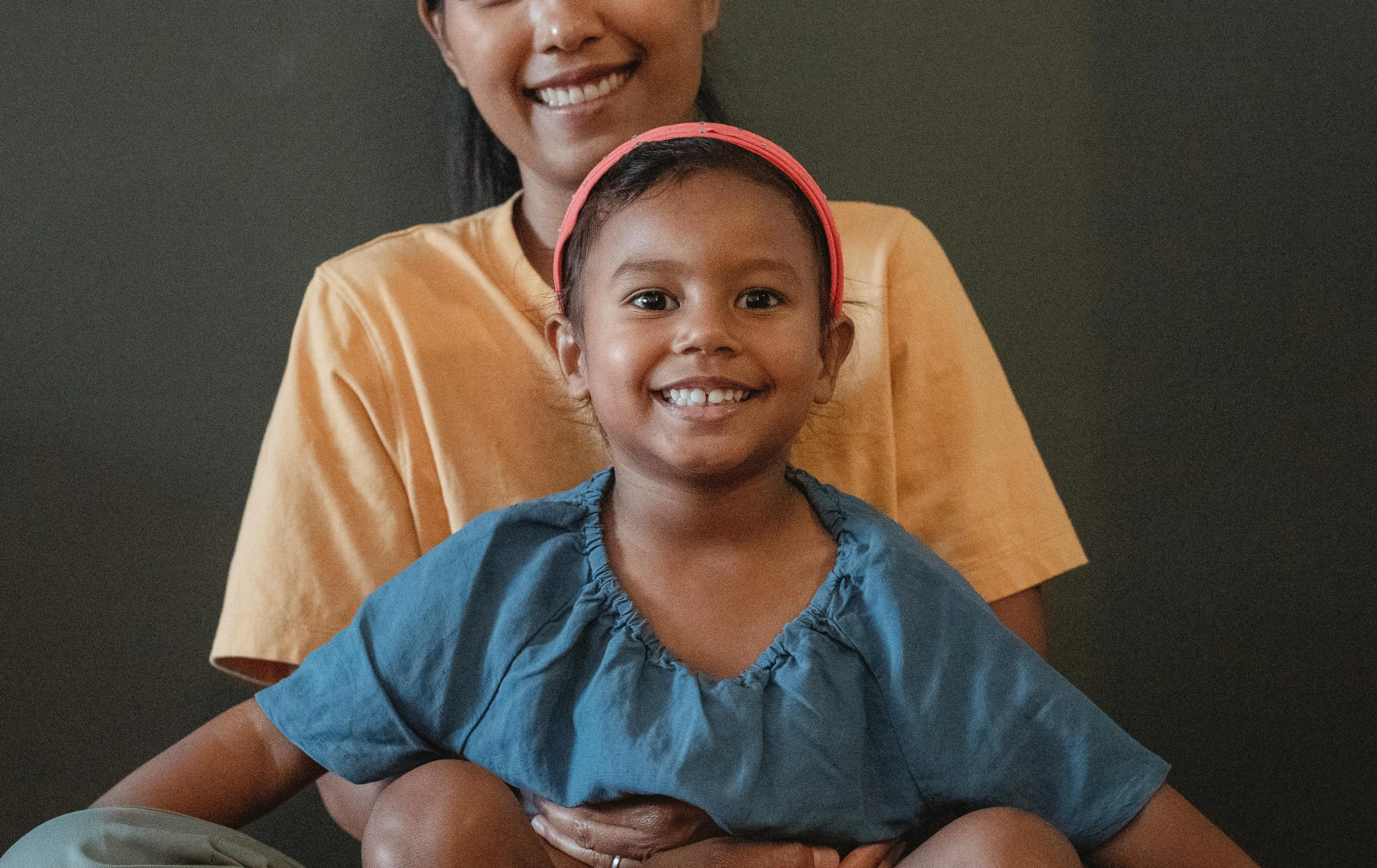 a woman and a child sitting next to each other, pexels contest winner, hurufiyya, slightly tanned, confident smile, nursing, coloured