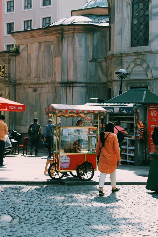a group of people walking down a cobblestone street, a picture, food stall, orange and teal color, istanbul, trending on vsco