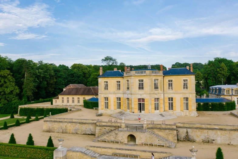 a large yellow building sitting on top of a lush green field, inspired by Pierre Mion, pexels contest winner, rococo, pur champagne damery, aerial, slide show, buildings carved out of stone