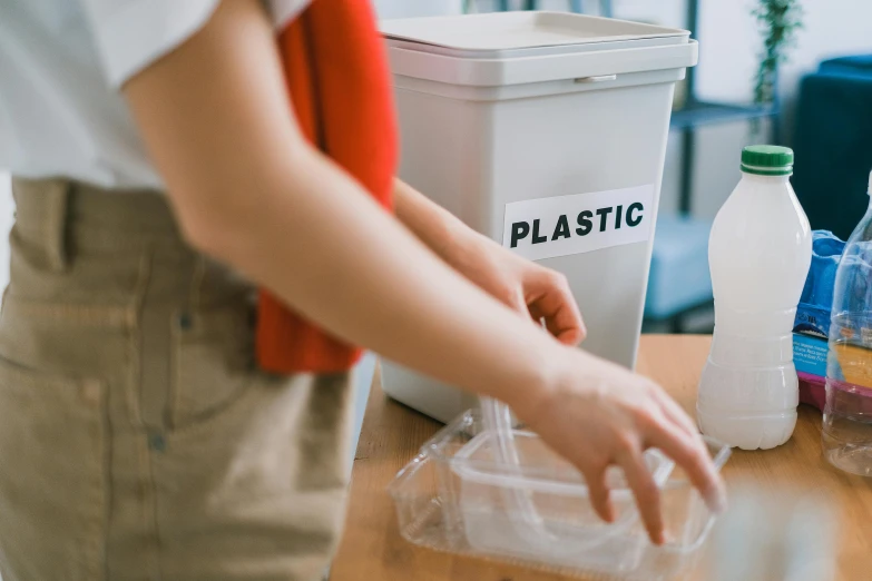 a person holding a plastic container on top of a table, pexels contest winner, sustainable materials, white, brown, avatar image