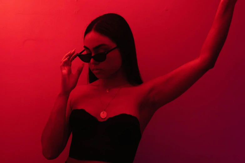 a woman standing in front of a red light, pexels contest winner, aestheticism, wearing bra, dark shades, lorde, charli bowater