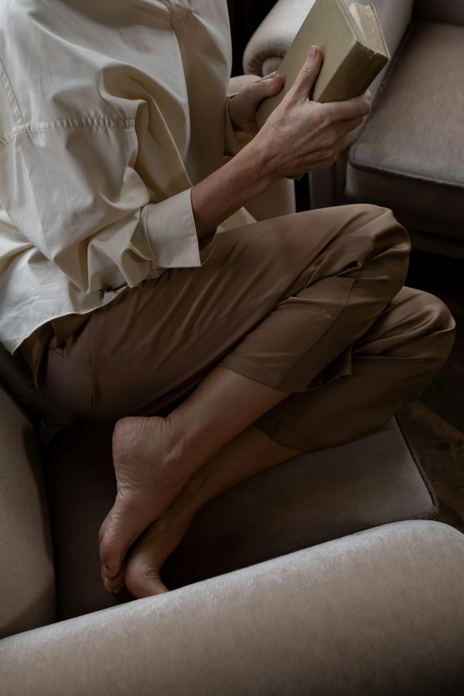 a man sitting in a chair reading a book, by Nina Hamnett, trending on unsplash, renaissance, brown pants, taupe, silky smooth, woman model