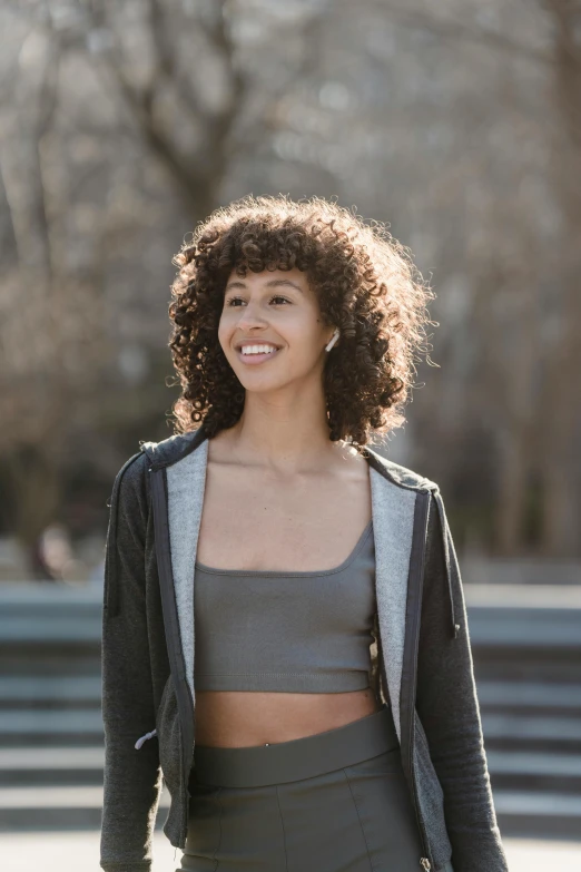 a woman riding a skateboard down a street, trending on pexels, dark short curly hair smiling, detailed sports bra, proud looking away, profile image