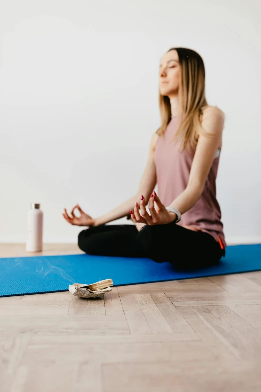 a woman sits on a yoga mat and meditates, by Rachel Reckitt, pexels contest winner, low quality photo, full body potrait holding bottle, high quality photo, advertising photo