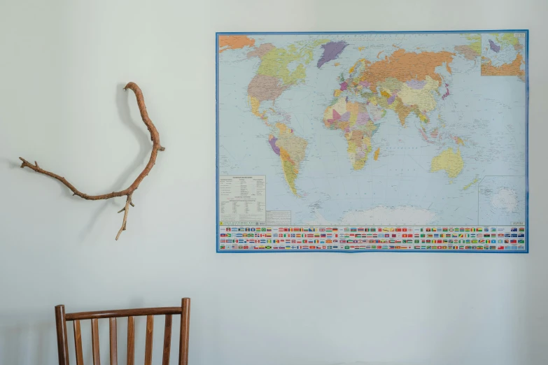 a wooden chair sitting in front of a map on a wall, a poster, inspired by Thomas Struth, unsplash, flags, 3 2 x 3 2, coloured in blueberra and orange, world tree