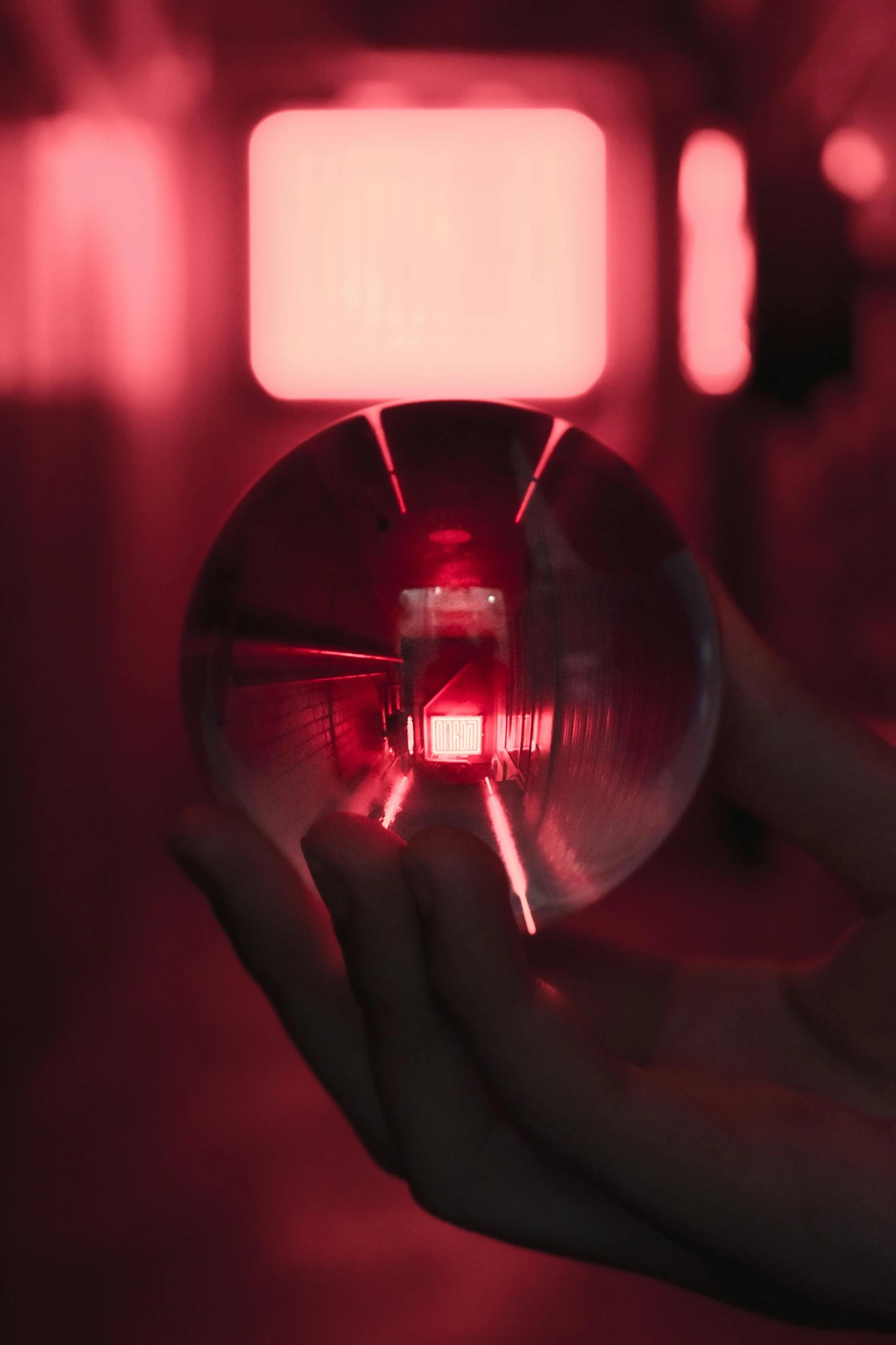 a person holding a crystal ball in their hand, inspired by Beeple, unsplash contest winner, holography, volumetric lighting. red, in a lab, light from right, red hue