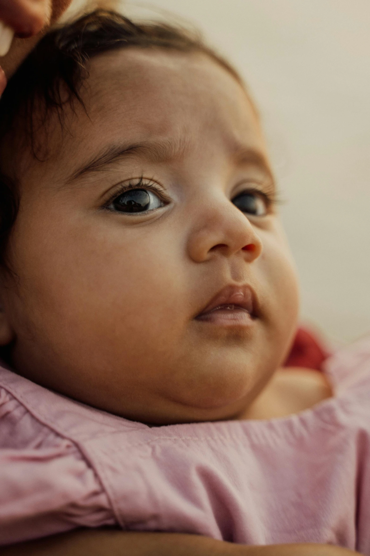 a close up of a person holding a baby, serious and stern expression, focused on her neck, olive skinned, screensaver